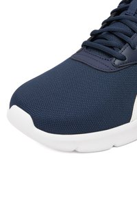 Tamsiai mėlynas sportinis batelis iš tinklelio, apvaliu priekiu, balta guminė sala ir plokščios raištelės. Lygaus sintetinio sluoksnio detalės prie priekinės dalies ir skylių raišteliams.