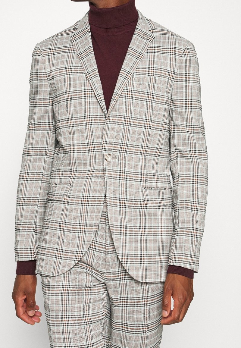 Geruite blazer in beige, bruin en wit. Beschikt over notch-kolven, een enkele knoop en twee zijzakken. De textuur lijkt glad.