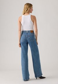 Lichtblauwe wijde spijkerbroek van denim, met een leren label op de achterste tailleband en een hoge taille. Soepele textuur.