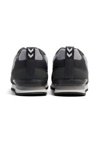 Czarne i szare buty sportowe z siateczkową i syntetyczną cholewką, teksturowanym obszarem pięty, gumową podeszwą oraz kontrastującym detalem w kształcie jodełki z tyłu.