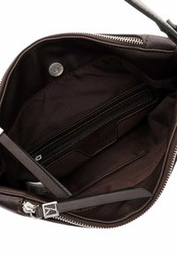 Ruskean nahkalaukun sisusta, jossa on sileä pinta, vetoketjullinen tasku, avotasku ja metallinen nepparikiinnitys.