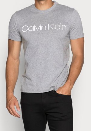 Graues T-Shirt mit kurzen Ärmeln aus Baumwolle in entspannter Passform. Verfügt über ein auffälliges weißes "Calvin Klein"-Logo auf der Brust.