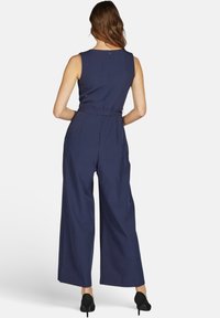 Navyblauwe jumpsuit met een fitted bodice, wijde broekspijpen en een ceintuur in de taille. Ritssluiting aan de achterkant en een gladde textuur.