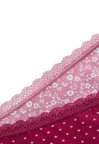 Tela con encaje en tonos rosas que presenta patrones florales y pequeños puntos metálicos, con una textura suave y un diseño en capas.