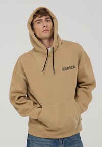 Felpa con cappuccio marrone, dotata di una grande tasca frontale, laccetti neri e testo "DARKER" in carattere nero sull'area sinistra del petto.