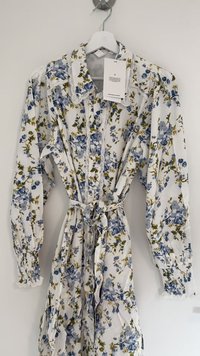 Rochie florală dintr-un material ușor, cu un fundal alb și flori albaștri și verzi, cu mâneci bufante și guler din dantelă.