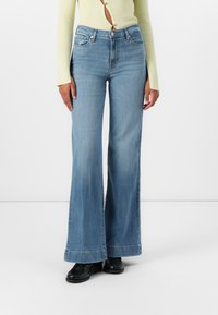 Jeans a zampa d'elefante blu chiaro con vita alta, chiusura con bottone, cinque tasche e orlo sfilacciato. Il tessuto ha una morbida trama in denim.