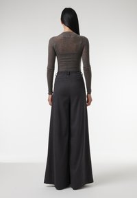 Grijze langwerpige fitted top gecombineerd met wijde, donkergrijze broeken met een elastische tailleband en achterzakken. Soepele textuur overal.