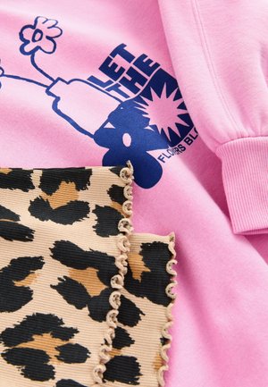 Rosa Sweatshirt mit blauem grafischem Text und Blumendesign; beiger Stoff mit schwarzem Leopardenmuster und Rüschensaum darunter.
