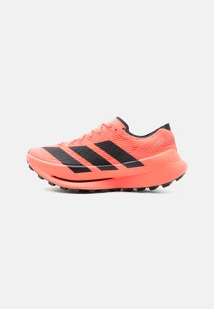 Różowo-koralowy but do biegania Adidas Terrex trail z czarnymi paskami, teksturowaną podeszwą i sznurowanym zapięciem, pokazany z zewnętrznej strony.