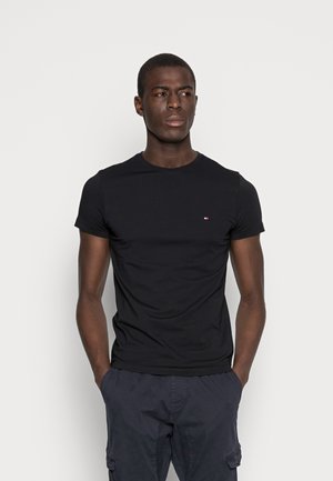 T-shirt noir à manches courtes en coton, arborant un petit logo sur la poitrine, coupe standard et col rond. Texture légère et lisse.