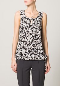 Sukienka bez rękawów w kolorze czarnym z białymi i szarymi okrągłymi wzorami, z wiązaniem na szyi i falbaniastymi akcentami na ramionach, wykonana z lekkiego materiału.