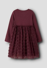 Maroonowa sukienka z długimi rękawami. Górna część jest z materiału prążkowanego, podczas gdy spódnica ma warstwową, teksturowaną tiul z wzorami róż.