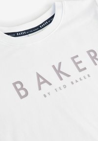Balta kokvilnas T-kreklu ar apaļu kaklu, ar teksturētu "BAKER" gaiši pelēkā krāsā un "by TED BAKER" mazākā fontā apakšā.