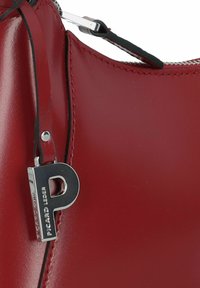Rode leren handtas met glanzende afwerking, zilverkleurige hardware en een leren label met een prominente letter "P". Details van de ritsluiting zichtbaar.