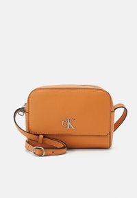 Calvin Klein orange leather crossbody bag with a rectangular shape, zip closure, and adjustable strap. Silver "CK" logo on front.