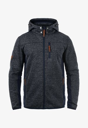 Dunkelgraue Fleecejacke mit einem marineblauen Seitenpanel, mit Reißverschlusstaschen, verstellbarem Kapuzen und braunen Lederelementen. Glatte Textur, enganliegender Stil.