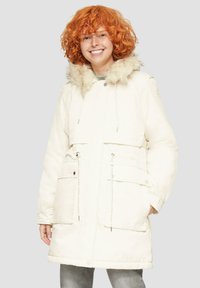 Biały park z kapturem wykończonym futrem, talią ze sznurkiem i przednimi kieszeniami. Miękka faktura i długość do kolan.