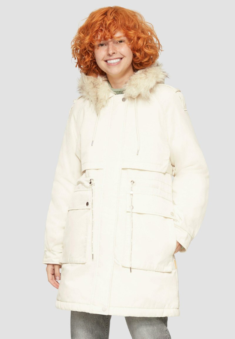 Biały park z kapturem wykończonym futrem, talią ze sznurkiem i przednimi kieszeniami. Miękka faktura i długość do kolan.