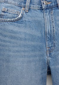 Světle modré džínové kalhoty s klasickým pětipocket designem, knoflíkovým zapínáním a viditelným šitím, s mírně vybledlou strukturou.