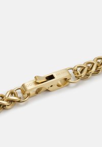 Gold metal chain featuring a sturdy clasp with the engraving "GUESS EST. 1981." Chain links have a smooth, polished finish.