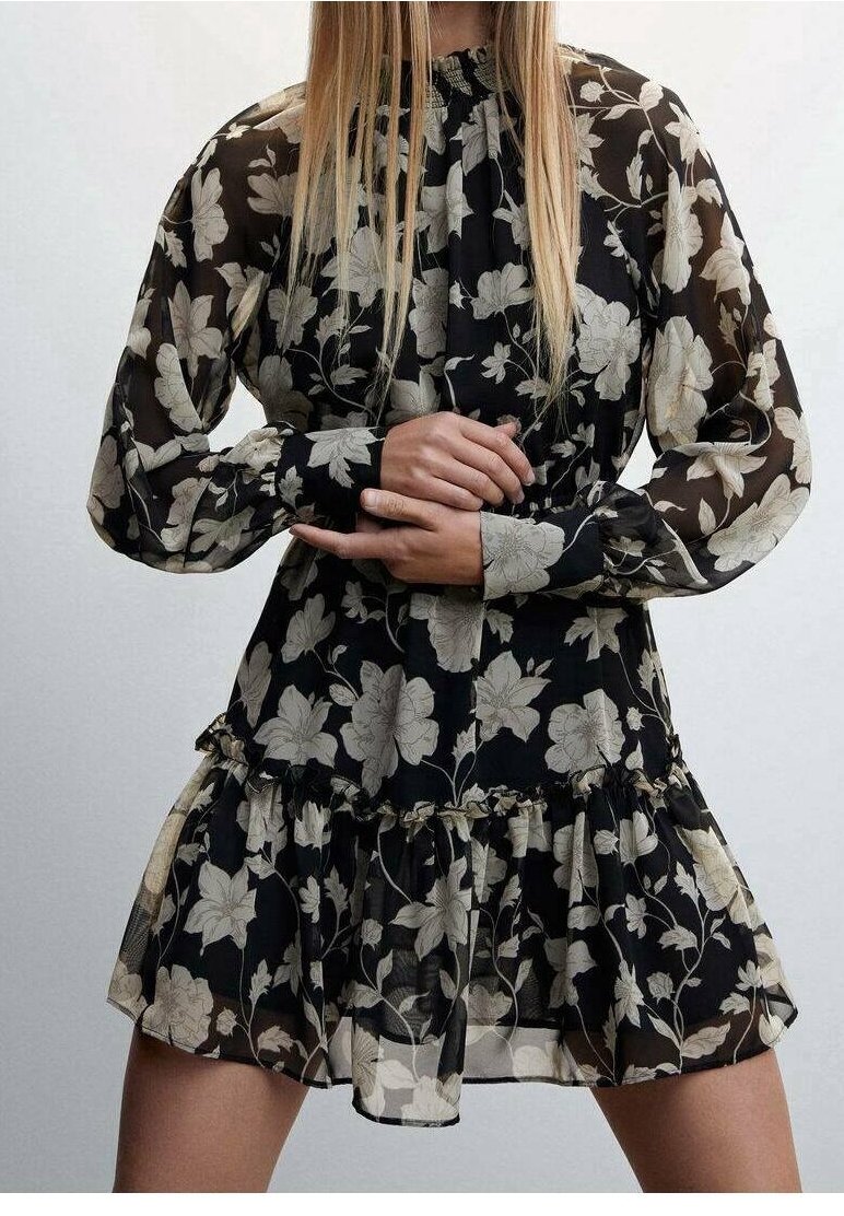 Robe noire à fleurs avec des manches longues, un ourlet volanté, un tissu transparent et des fleurs crème. Col haut et détails froncés à la taille.