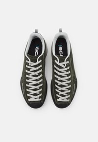 Grønne semskede sneakers med grå snørebånd, teksturert tunge og gummisåler. Har "Scarpa" merkevare på siden.