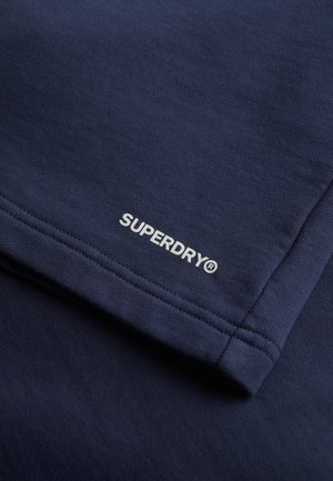 Dark blue cotton fabric with a smooth texture. Features white "SUPERDRY" logo embroidery on the hem, with flat seams along the edges.