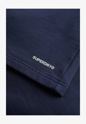 Dark blue cotton fabric with a smooth texture. Features white "SUPERDRY" logo embroidery on the hem, with flat seams along the edges.