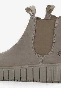 Bottines taupe à enfiler avec panneaux élastiques sur les côtés, languettes de traction et semelles en caoutchouc épaisses rainurées.