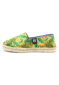 Chaussure espadrille jaune ornée de motifs de feuilles tropicales vertes et de fleurs, avec une semelle en corde de jute et une doublure bleue.
