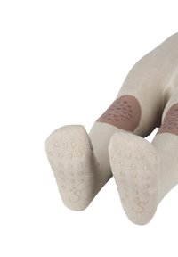 Beige Socken mit braunen rutschfesten Punkten und einem abgerundeten Zehendesign. Weicher Stoff, elastisch für Komfort, mit einem Logo auf der Unterseite.