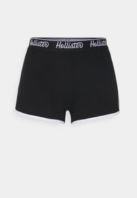 Černé bavlněné šortky s bílým lemem, které mají značkový elastický pas s nápisem "Hollister" v bílém písmu.