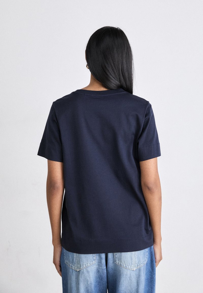 Marineblaue Baumwoll-T-Shirt mit kurzen Ärmeln und Rundhalsausschnitt, von hinten betrachtet, mit einem einfachen, klaren Design und weicher Textur.