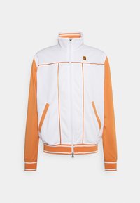 Chaqueta deportiva de cremallera blanca y naranja, con un alto cuello, bolsillos laterales, puños de canalé y detalles de piping en contraste.