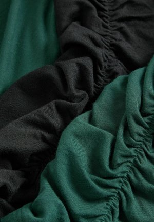 Schwarze und grüne Stoffabschnitte mit geraffter Textur. Das Schwarz ist dunkel und glatt, während das Grün leicht glänzend und weich ist.