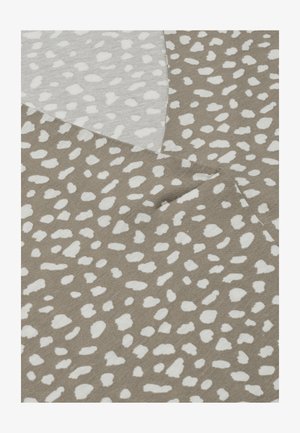 Beige stof med et ujævnt hvidt plettet mønster, vist foldet med synlig tekstur og vævning.