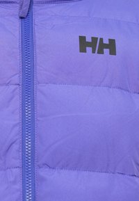 Giacca a vento viola con zipper frontale, caratterizzata da pannelli cuciti e un logo nero sul petto. Il materiale appare liscio e leggero.