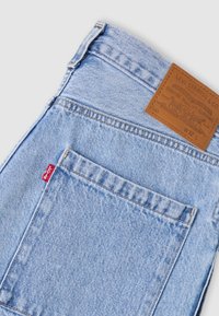 Τσέπη από ανοιχτό γαλάζιο τζιν με κόκκινη ετικέτα Levi's και καφέ δερμάτινη ετικέτα Levi Strauss & Co. που δείχνει το μέγεθος W32 L.