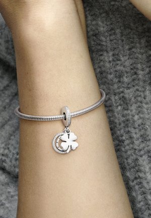 Silbernes Armband mit geflochtenem Design, das einen Hufeisen- und einen Kleeblatt-Anhänger zeigt, akzentuiert durch funkelnde Details.