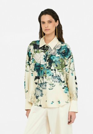 Blusa floreale in crema chiaro con accenti in teal e verde; presenta un colletto a punta, chiusura con bottoni e maniche lunghe con una vestibilità rilassata.