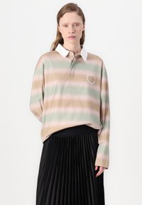 Polo de riscas claras em verde, rosa e bege, com colarinho branco e um detalhe bordado circular. Combinado com uma saia preta plissada.