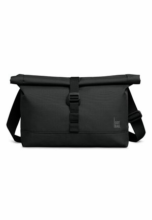 Schwarze Roll-Top Messenger-Tasche mit verstellbarem Schultergurt und vorderem Schnallenverschluss, mit kleinem "GOT BAG" Logo unten rechts.