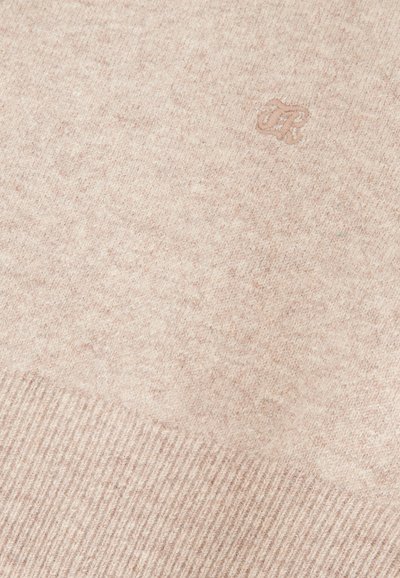 Suéter de punto beige claro con un patrón texturizado, dobladillo acanalado y un logotipo bordado en la esquina superior izquierda.