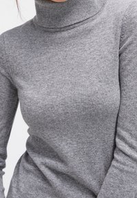 Grå turtlenecktröja i mjukt, stretchigt trikåtyg. Har en hög krage och en figurnära design, med en slät och jämn textur.