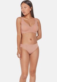 Ensemble de bralette et culotte hipster de couleur chair sans couture, featuring un tissu doux, un design en v et un style minimaliste.