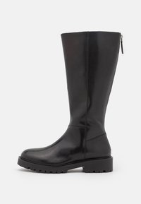 Bota de cuero negro hasta la rodilla con un acabado suave, suela de goma gruesa y cremallera lateral para facilitar su uso. Presenta un diseño minimalista.