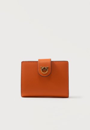 Portefeuille en cuir orange avec une fermeture à languette ornée d'un emblème doré représentant deux oiseaux, présenté sur un fond blanc uni.