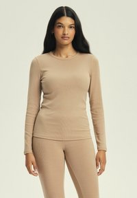 Jasno beżowy, długi rękaw, prążkowany top wykonany z miękkiego materiału, z okrągłym dekoltem, w zestawie z dopasowanymi prążkowanymi spodniami; dopasowany krój.