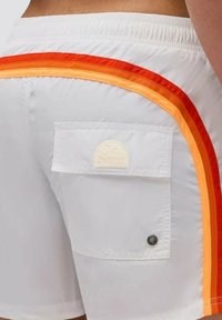 Bañador blanco con franjas vibrantes en naranja y rojo a lo largo de los lados, con un bolsillo trasero y una etiqueta de logo texturizada.